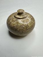 Front view of small polished green stone round box with lid attached