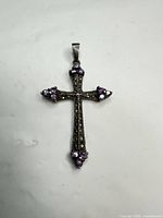 Front view of sterling silver cross pendant showing full design and purple stones