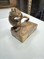 Front-left view showing feline figure, tail, and rectangular base