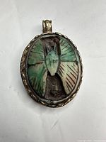 front view of oval silver pendant with carved turquoise insect cabochon