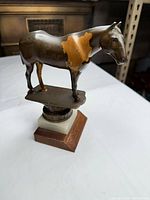 Front three-quarter view showing horse figurine, layered bases, surface wear