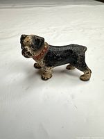 left side view of cast iron dog figurine showing black paint and red collar