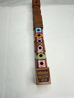 Top view showing carvings, coloured hole rims and tiki face