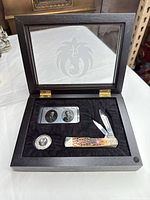 Full presentation case open showing pocket knife, medallion coin and portrait plaque; etched Ruger logo on glass lid visible