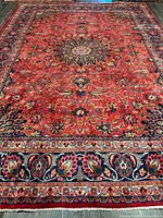 Full view of Persian Mashhad rug showing red field, central medallion, floral motifs and borders