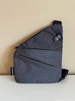 Front view of dark grey sling-style bag with angled seams