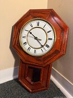 Front view of octagonal oak wall clock leaning against wall