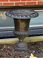 Full view of cast iron urn planter in garden