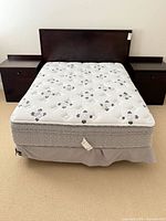 Full view of mattress on boxspring between nightstands