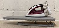Small tabletop ironing board with T-fal iron on top, cords wrapped