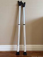 Pair of white adjustable security bars standing against wall
