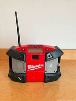 Front view of Milwaukee M12 job-site radio showing speakers, logo and antenna