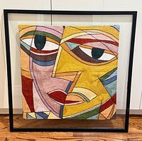 Full view of framed embroidered cubist artwork on wall