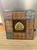 Front view showing mixed materials, central leaf motif, rattan slats, embossed metal corners