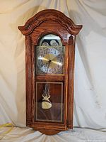 Full front view of Howard Miller oak pendulum wall clock