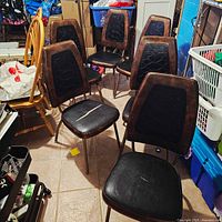 Group of six brown/black vinyl dining chairs showing overall design and quantity