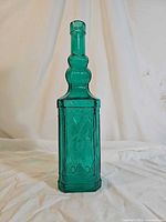 Front view of emerald green embossed glass bottle