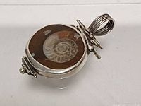 Front angled view showing ammonite fossil and silver bezel