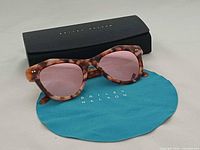 Sunglasses on cloth with case behind showing branding