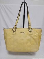 Front view of yellow Coach Gallery patent leather tote showing overall design, straps and logo
