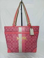 Front view of Coach pink monogram tote showcasing stripe, logo, shape and straps