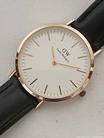 Front view of watch showing white dial, gold-tone markers, hands, and rose-gold-tone case