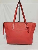 Front view of red Fossil Sidney tote with straps and key charm visible