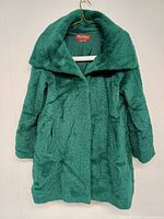 Front view of green textured coat hanging
