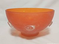 Side view of frosted orange glass bowl showing applied circular accent