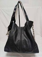 front view of Michael Kors black pebbled leather shoulder bag showing vertical seam and strap