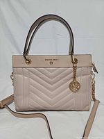 Front view showing quilted pattern, handles, logo, charm