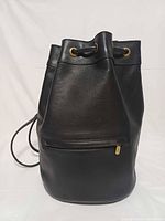 Front view showing pebbled leather, drawstring closure, front zip pocket