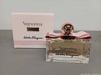 Front view of perfume bottle beside front of box