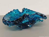 Side view of blue Murano art glass ashtray showing ruffled edge and applied clear lobes
