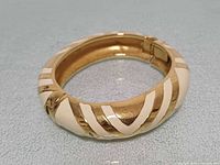 Top view of gold-tone cream enamel hinged cuff bangle