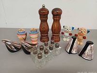 group shot of all shakers including wood, ceramic, chrome bird, glass set, dog, lattice