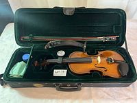 Open case showing violin, bow, shoulder rest, rosin, cloth