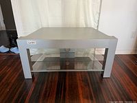 Front view of silver console table showing top surface and two glass shelves