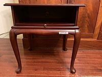 Front view showing open shelf, pull-out tray, cabriole legs
