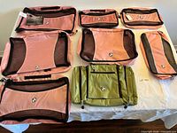 Full set of six pink packing cubes and one green organizer displayed on table