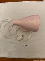 Side view of pink wall lamp, cord and inline switch visible