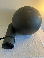 Yoga mat rolled with strap next to PuRathletics exercise ball