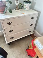 Front view showing three drawers, drop handles, hairpin legs, distressed paint