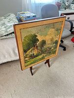 Front view of folding card table with printed landscape top displayed upright