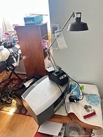 Bose Wave unit, desk lamp, remote, power cord and manuals visible on table