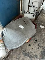 Stack of gray, burgundy and beige carpet floor mats on floor beside water heater