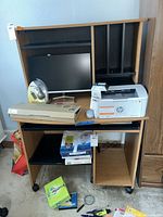 Front view of desk showing monitor area, keyboard tray, printer shelf, casters