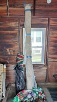 Tall roll of cream damask curtain fabric wrapped in plastic with MaxSold tag, striped curtain bundle and bag of bows at base