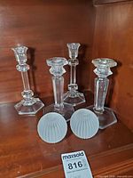 Four glass candlesticks and two frosted globes displayed on shelf