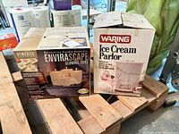 Both boxed items on pallet: HoMedics Envirascape candle fountain and Waring Ice Cream Parlor ice cream maker